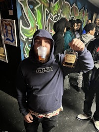 a man in a hoodie holding a beer